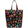 A black tote bag featuring a vibrant, repeating pattern of colorful Sacred Heart of Jesus motifs, complete with two shoulder straps, shown against a plain white background.