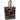 A black tote bag featuring a vibrant, colorful pattern of traditional Mexican Sacred Heart of Jesus motifs, including hearts with wings, flowers, and religious symbols. The bag has two shoulder straps and a small gold-tone brand plaque on the front.