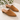 A pair of tan suede mule heels with pointed toes and low block heels, displayed on a light stone surface with green leaves in the top left. The brand name 'CORDANI ITALY' is printed on the insole.