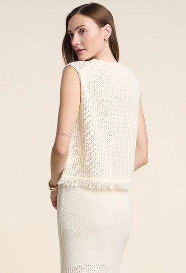 Woman wearing a cream-colored sleeveless top against a plain background