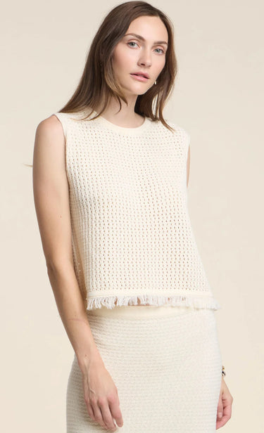 Woman wearing a sleeveless cream sweater vest against a beige background
