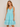 Woman wearing a light blue dress with lace details on a beige background