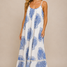 Woman wearing a white dress with blue patterns against a beige background