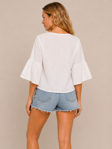 Woman wearing a white blouse and denim shorts against a beige background