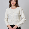 a woman wearing a white sequin cardigan and black leggings on a white background