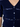 A woman wearing a navy short sleeve v-neck cardigan with blue sequin stripes and black jeans on a neutral background