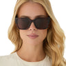 Woman wearing tortoiseshell sunglasses with a neutral background