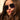 Close-up of a woman wearing large purple sunglasses with a neutral background