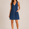 Woman wearing a blue denim dress with a zipper on a beige background