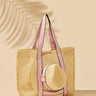 Woven straw bag with pink straps and a matching straw hat on a beige background