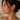 Close-up of a woman wearing gold hoop earrings with a neutral background