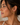 Close-up of a woman wearing gold hoop earrings with a neutral background