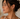 Close-up of a woman wearing gold hoop earrings with a neutral background