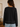 Person wearing a black sweater with white trim in an indoor setting