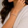 Close-up of a woman wearing a silver bracelet on a neutral background
