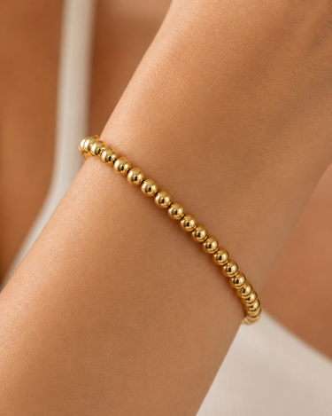 A woman wearing a gold beaded bracelet