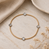A gold beaded bracelet with mother of pearl clover charms on a table