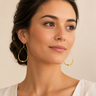 A woman wearing Gold beaded teardrop earrings 