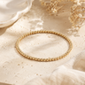 a 3mm gold beaded bracelet on a neutral background 
