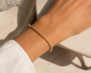 A woman wearing a 3mm gold beaded bracelet