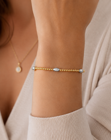 a woman wearing a oval silver and circle gold beaded bracelet