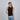 Woman wearing a black tank top and blue jeans on a plain background