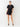 Woman wearing a black romper with buttons on a white background