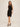 Woman wearing a black dress against a beige background