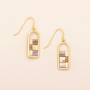 Gold earrings with mosaic design on a beige background