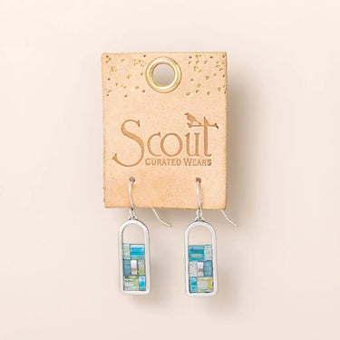 A pair of silver-toned drop earrings with rectangular mosaic inlays in shades of blue, green, and white, displayed on a tan cardboard card printed with the brand name 'Scout Curated Wears' against a light beige background.