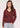 a woman wearing a deep wine red v-neck pullover sweater and blue jeans on a white background 