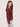 a woman wearing a deep wine red v-neck pullover sweater and blue jeans on a white background 