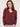 a woman wearing a deep wine red v-neck pullover sweater and blue jeans on a white background 