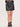 A woman wearing a faux leather skirt in black with brown loafers on a white background.