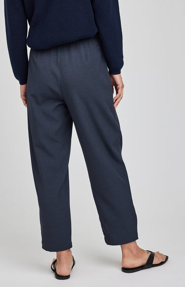 Person wearing navy blue pants and a sweater on a white background