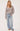 A woman wearing a knit heather v-neck cardigan and blue jeans on a white background