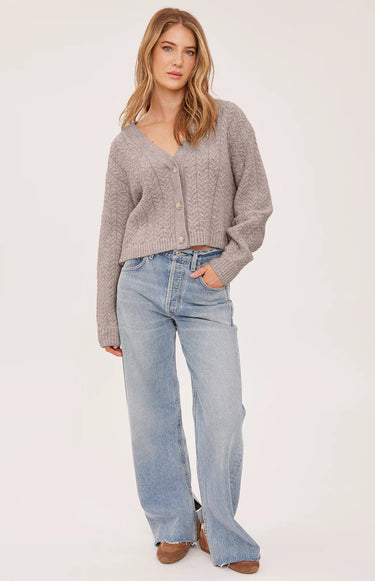 A woman wearing a knit heather v-neck cardigan and blue jeans on a white background