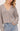 A woman wearing a knit heather V- neck cardigan and blue jeans on a white background