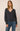 A woman  wearing a gray ribbed v-neck sweater and jeans on a white background