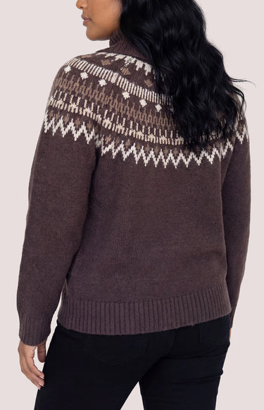 A woman facing backward in a brown turtle neck with a fair isle print and black jeans on a white background.