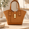 Camel suede handbag with gold hardware shown from a front  angle on a neutral travertine table.