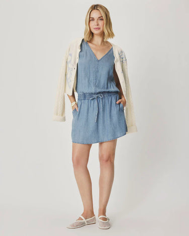 Woman wearing a blue dress with a beige cardigan on a white background