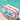 White pouch with 'Hello Weekend' text in colorful letters, placed on a sandy surface with a pool in the background.