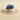 Multicolored straw hat with blue, beige, and gray sections on a beige background
