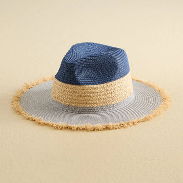 Multicolored straw hat with blue, beige, and gray sections on a beige background