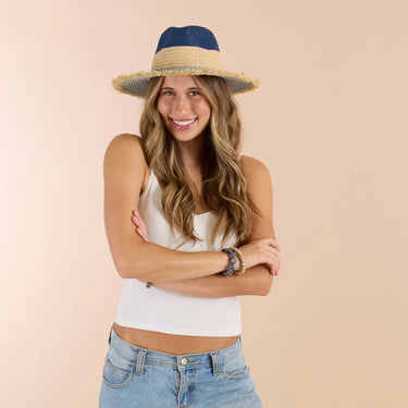 Woman wearing a straw hat with a blue band on a beige background