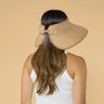Woman wearing a beige visor with a bow on a beige background