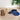 Two straw visors, one brown and one blue, on a wooden surface with a plant in the background.