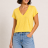 Woman wearing a yellow top and blue jeans against a plain background