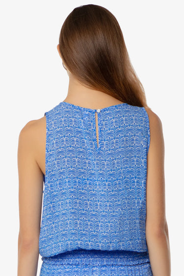 Woman wearing a blue sleeveless top with a white pattern on a white background